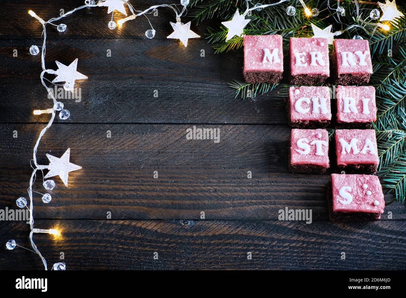 Honigkuchen Frohe Weihnachten mit rot gefärbten Glasur braun Holztisch, schön angeordnet, eingerahmt von einer Kette von Lichtern, weihnachten flach legen Stockfoto