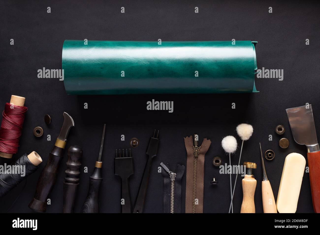 Rolle aus grünem Leder und verschiedene Werkzeuge für die Handarbeit Lederprodukte. Stockfoto