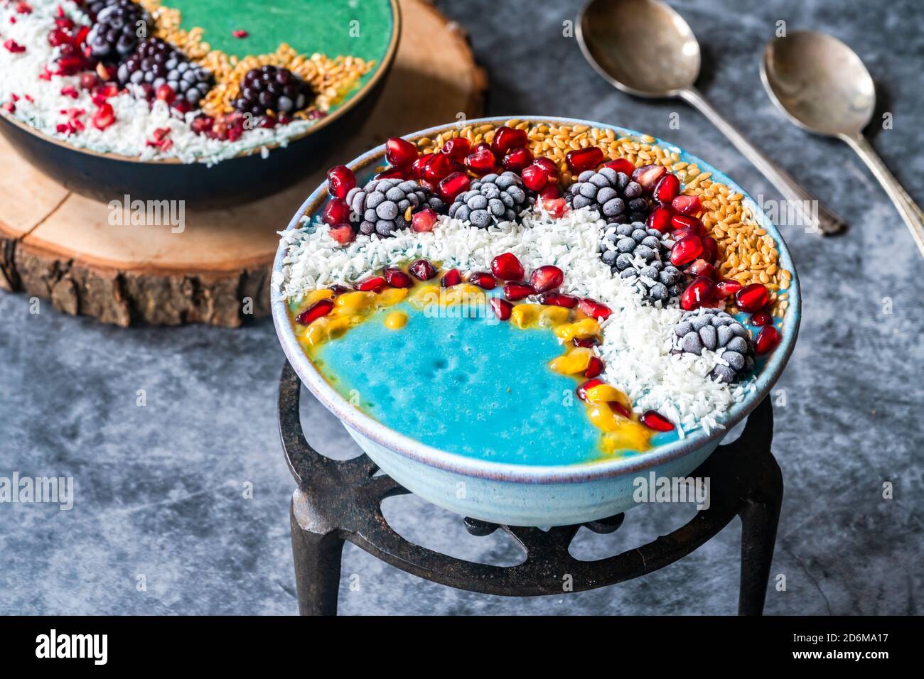 Blaue und grüne Spirulina Smoothie Schalen mit Obst und Leinsamen - gesunde Superfood Frühstücksidee. Stockfoto