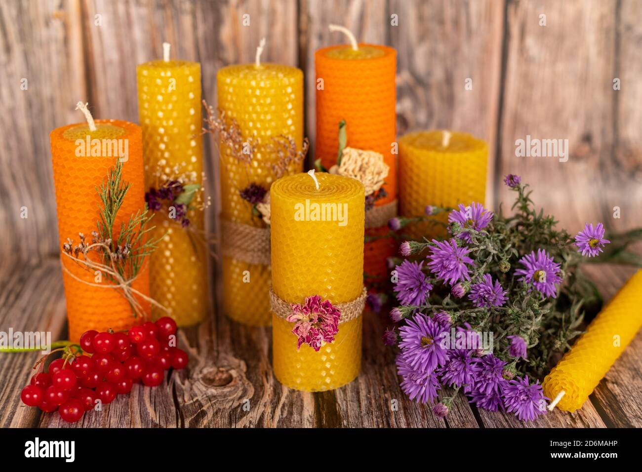 Handgemachte gelbe Honigkerzen aus Naturwachs auf einem Hintergrund aus Holzbrettern. Elemente aus natürlichen Materialien. Komposition zu Weihnachten oder Neujahr Stockfotografie