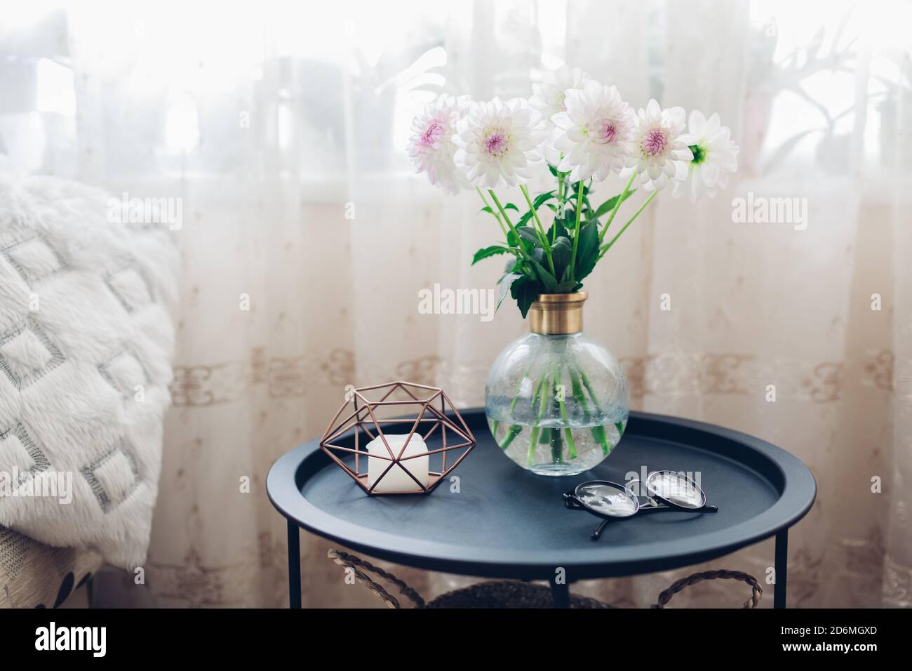 Interieur des Wohnzimmers mit Blumen auf Couchtisch mit Kerze und Gläser dekoriert. Frische Dahlien Stockfoto