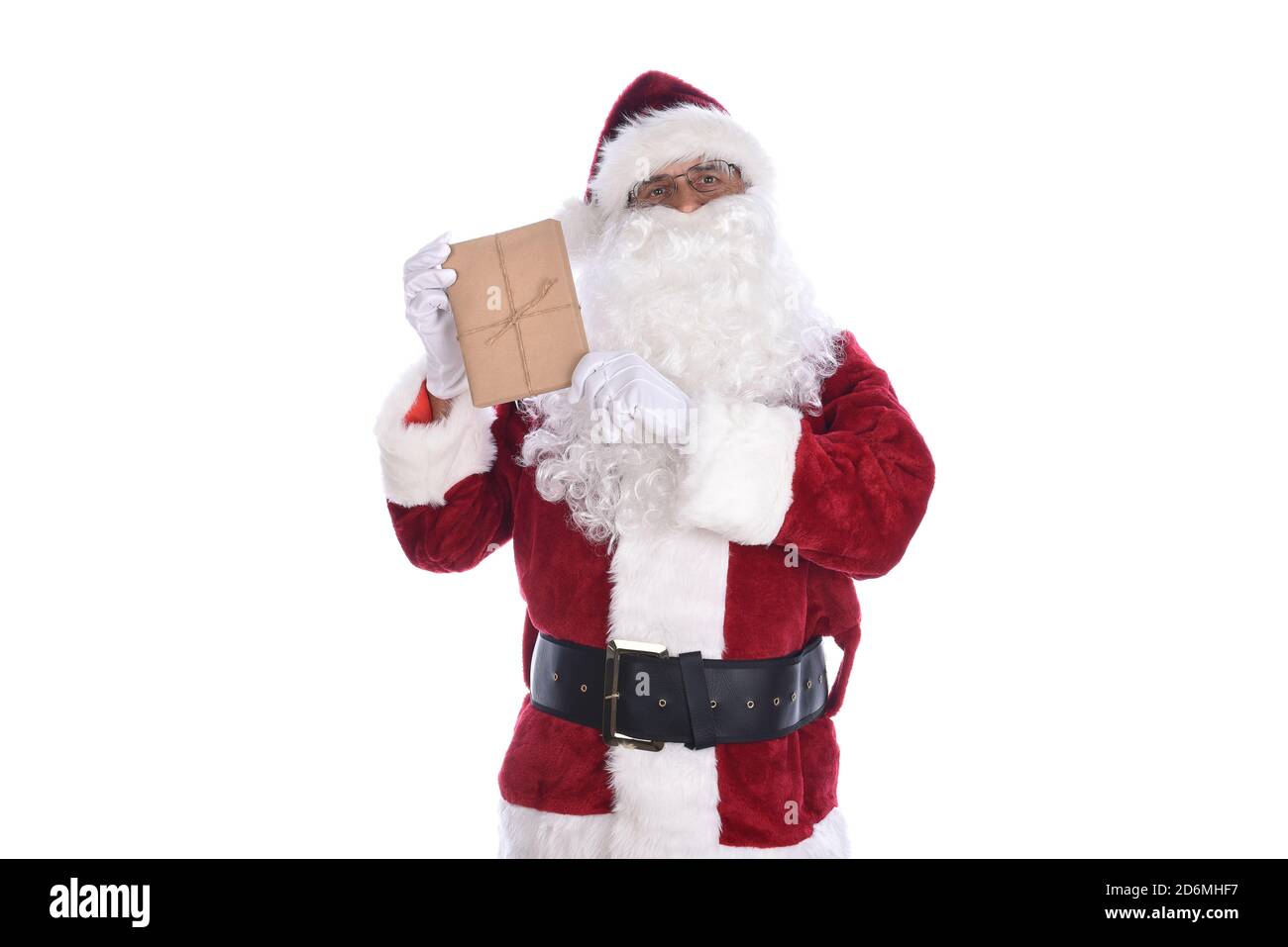 Älterer Mann trägt ein traditionelles Weihnachtsmann Kostüm und hält ein schlichtes braunes Papier eingewickeltes Geschenk in seinen Händen. Isoliert auf Weiß. Stockfoto