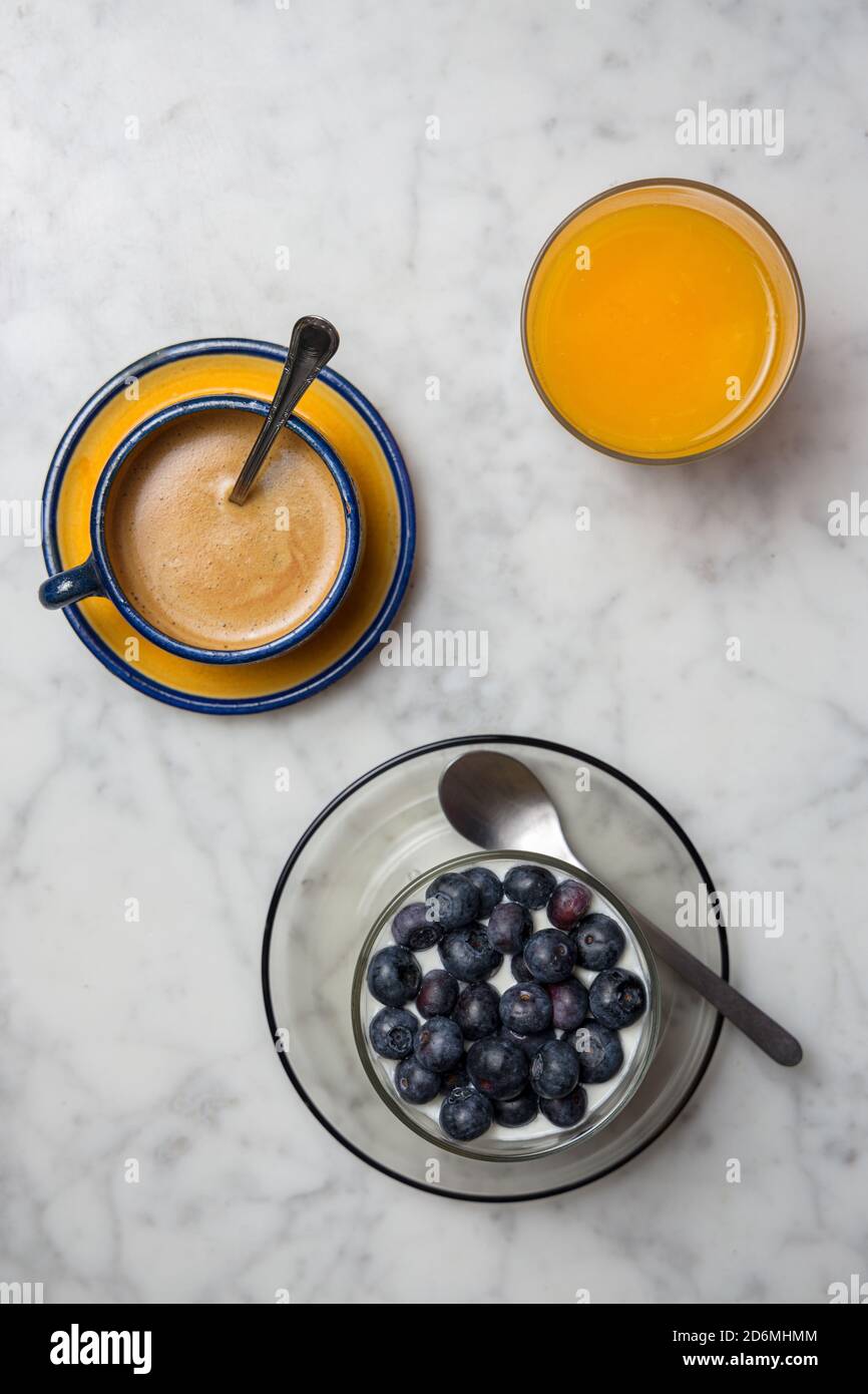 Gesundes Frühstück mit Müsli, Joghurt und Obst, Kaffeetasse und Orangensaft Stockfoto