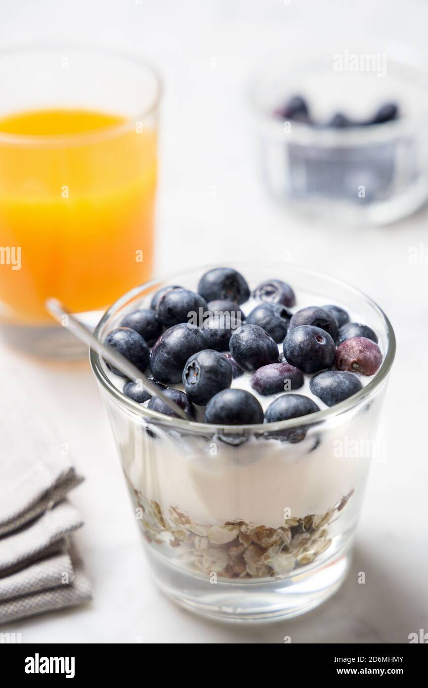 Gesundes Frühstück mit Müsli, Joghurt und Obst, Kaffeetasse und Orangensaft Stockfoto