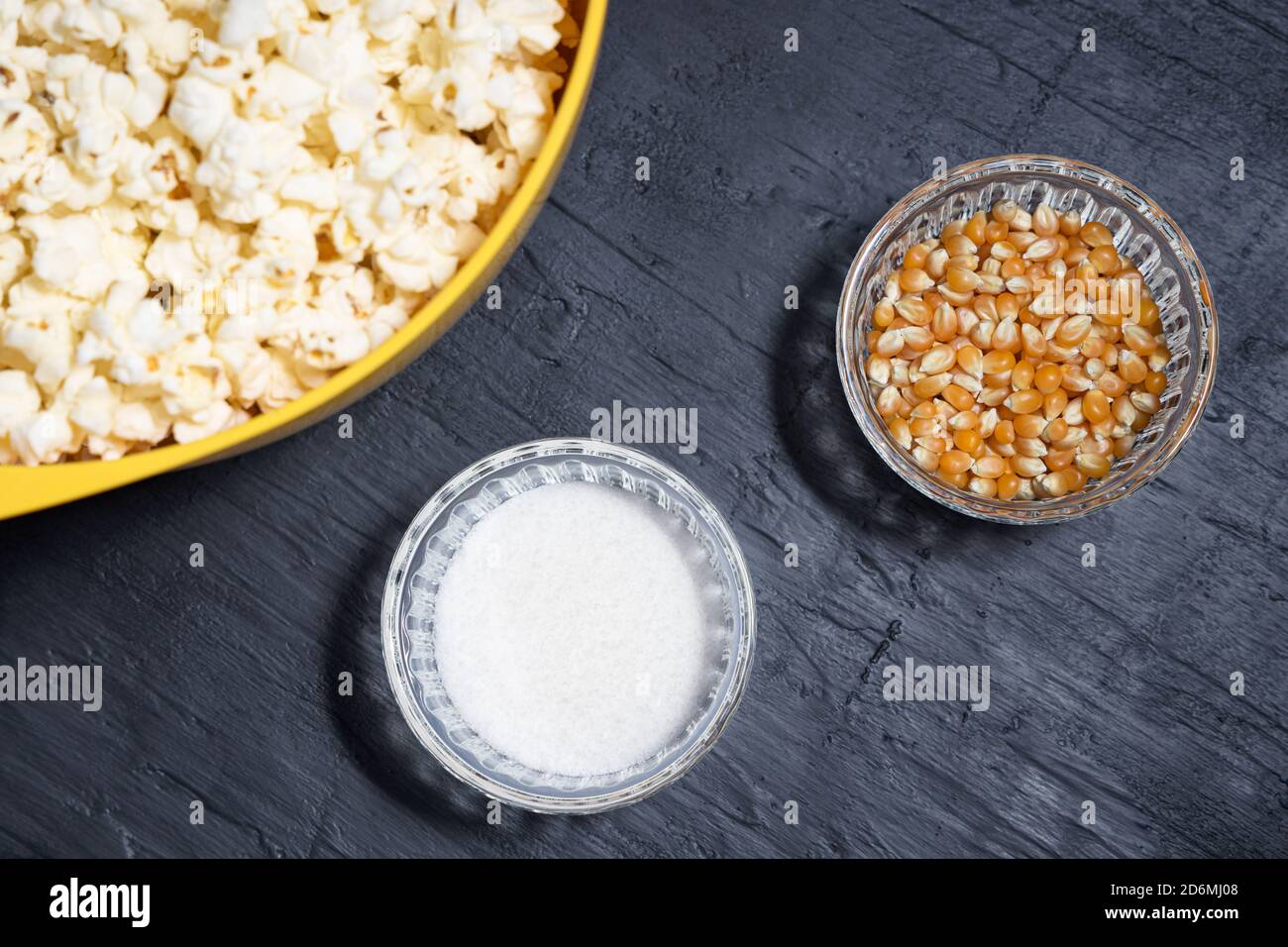 Popcorn in einer gelben Schüssel neben Maiskörnern und Salz Stockfoto