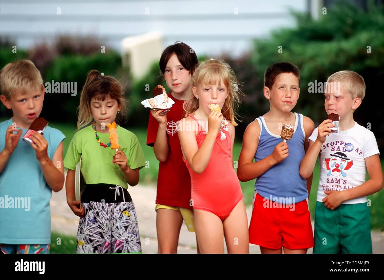 Sechs 5-7 Jahre männliche und weibliche Kinder mit Spaß Linie Bis zu Eis Leckereien essen Stockfoto