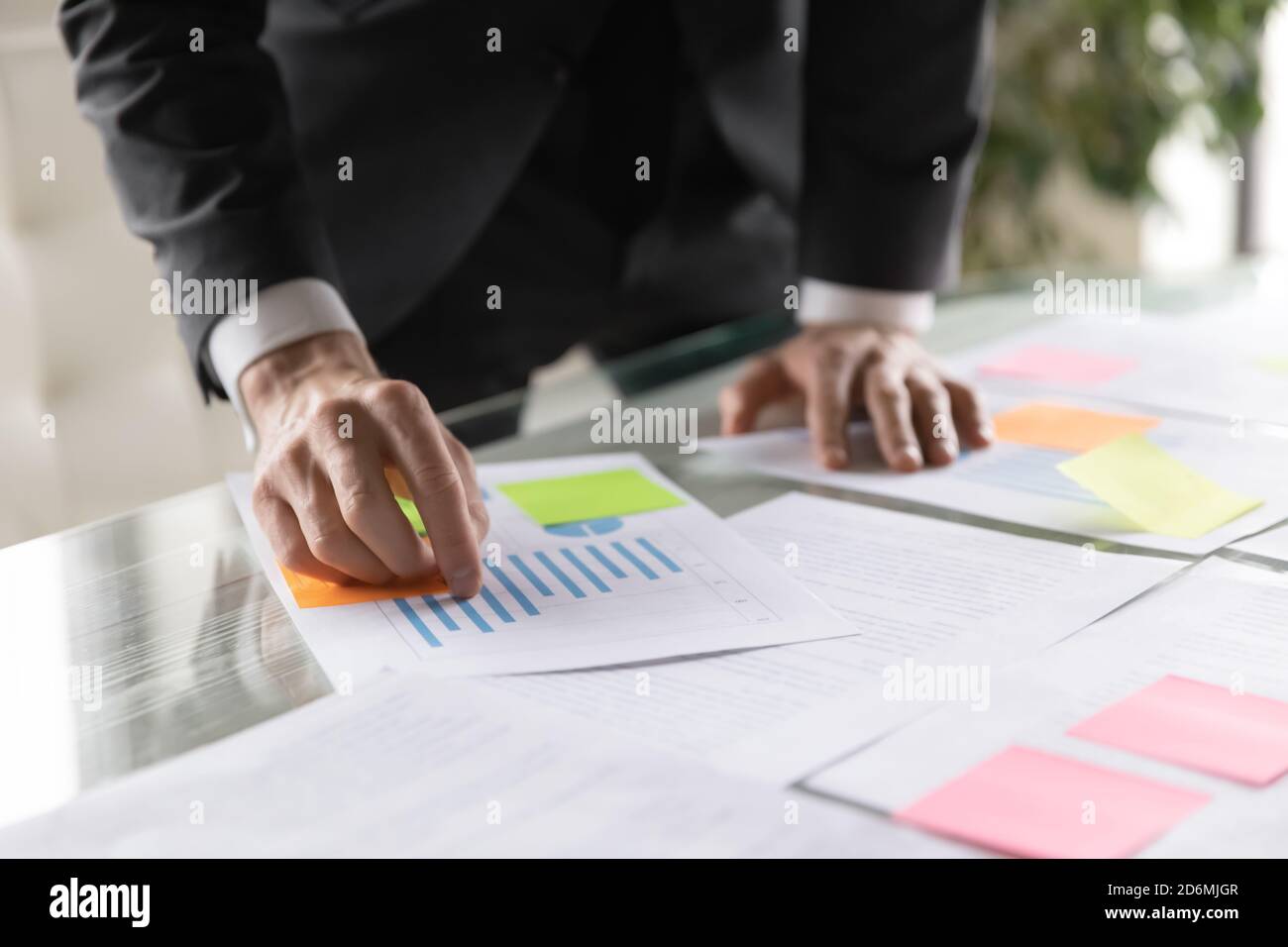 Nahaufnahme junger männlicher Angestellter in Anzug analysiert Papierbericht. Stockfoto