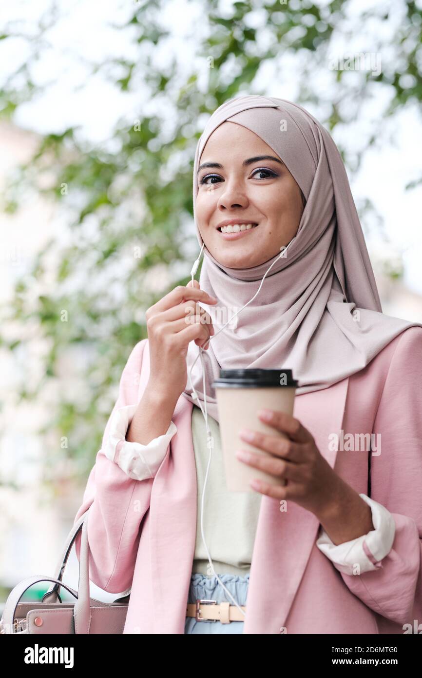 Junge wunderschöne lächelnde muslimische Frau mit einem Glas Kaffee telefonieren Jemand Stockfoto