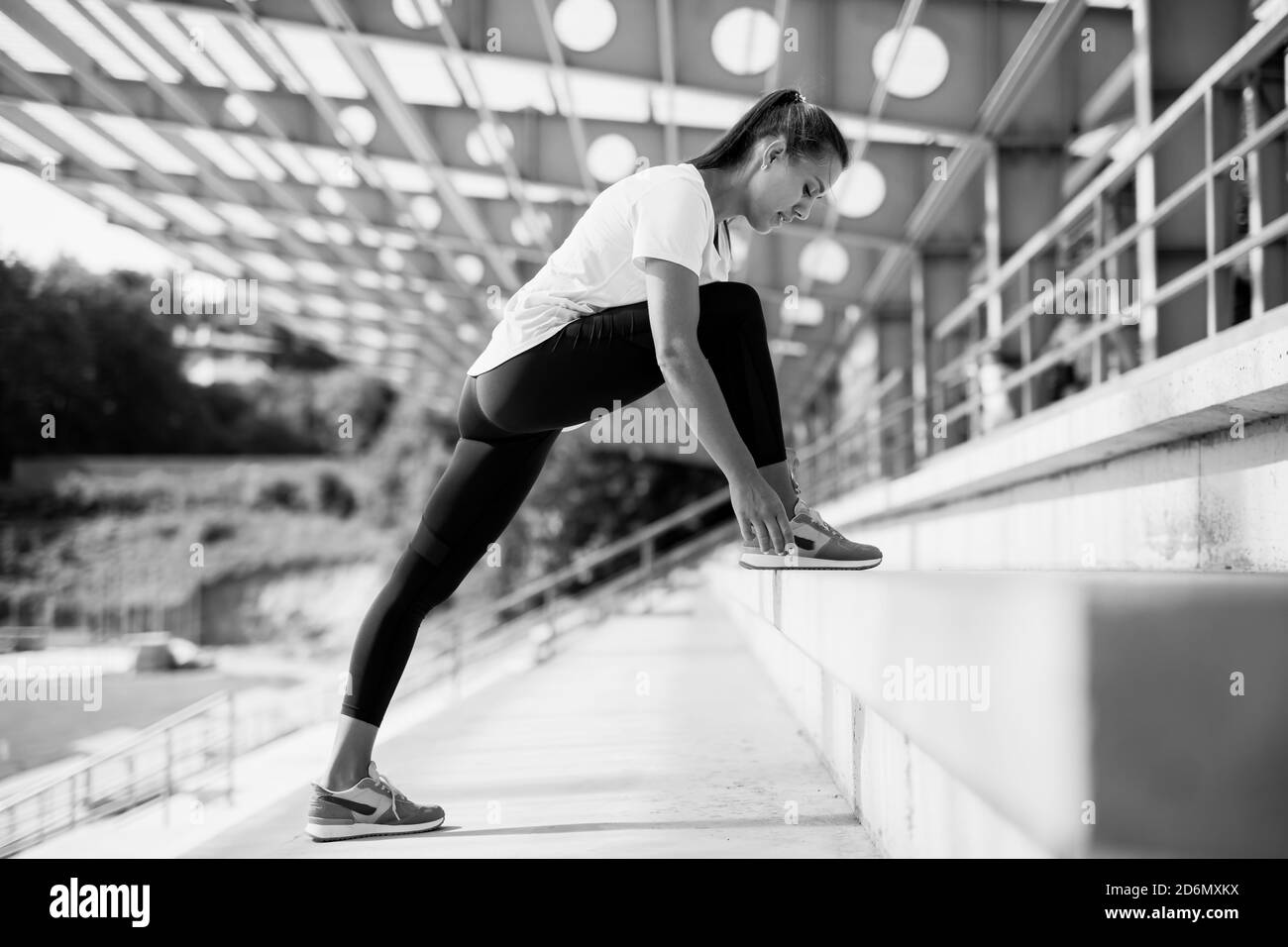 Junge Fitness-Frau in Sportbekleidung Stretching Beine auf Treppen Stockfoto