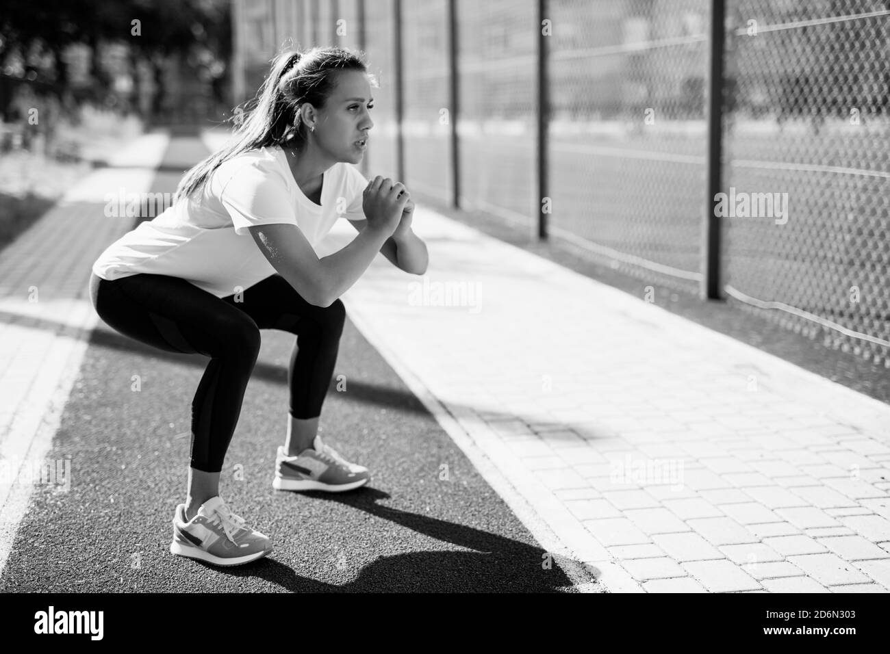 Motivierte Frau tut tiefe Kniebeugen an der frischen Luft Stockfoto