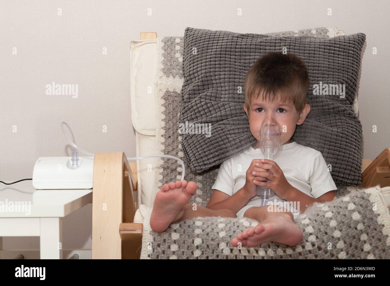 Kleiner kranker Junge mit Vernebler Maske macht Inhalation, Atemwegsprozedur durch Lungenentzündung oder Husten für Kind zu Hause. Stockfoto