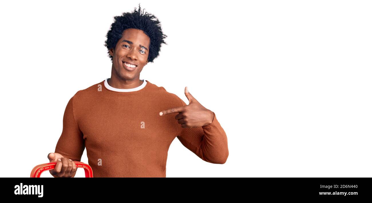 Schöner afroamerikanischer Mann mit afro Haar hält Supermarkt einkaufen Korb zeigt Finger auf ein selbst lächeln glücklich und stolz Stockfoto