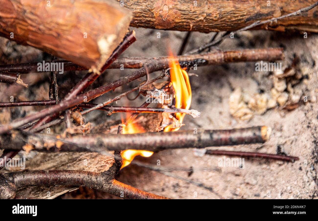 Feuer auf Holzstämmen entzünden. Das erste Feuer auf dünnen Stäben. Nahaufnahme. Stockfoto