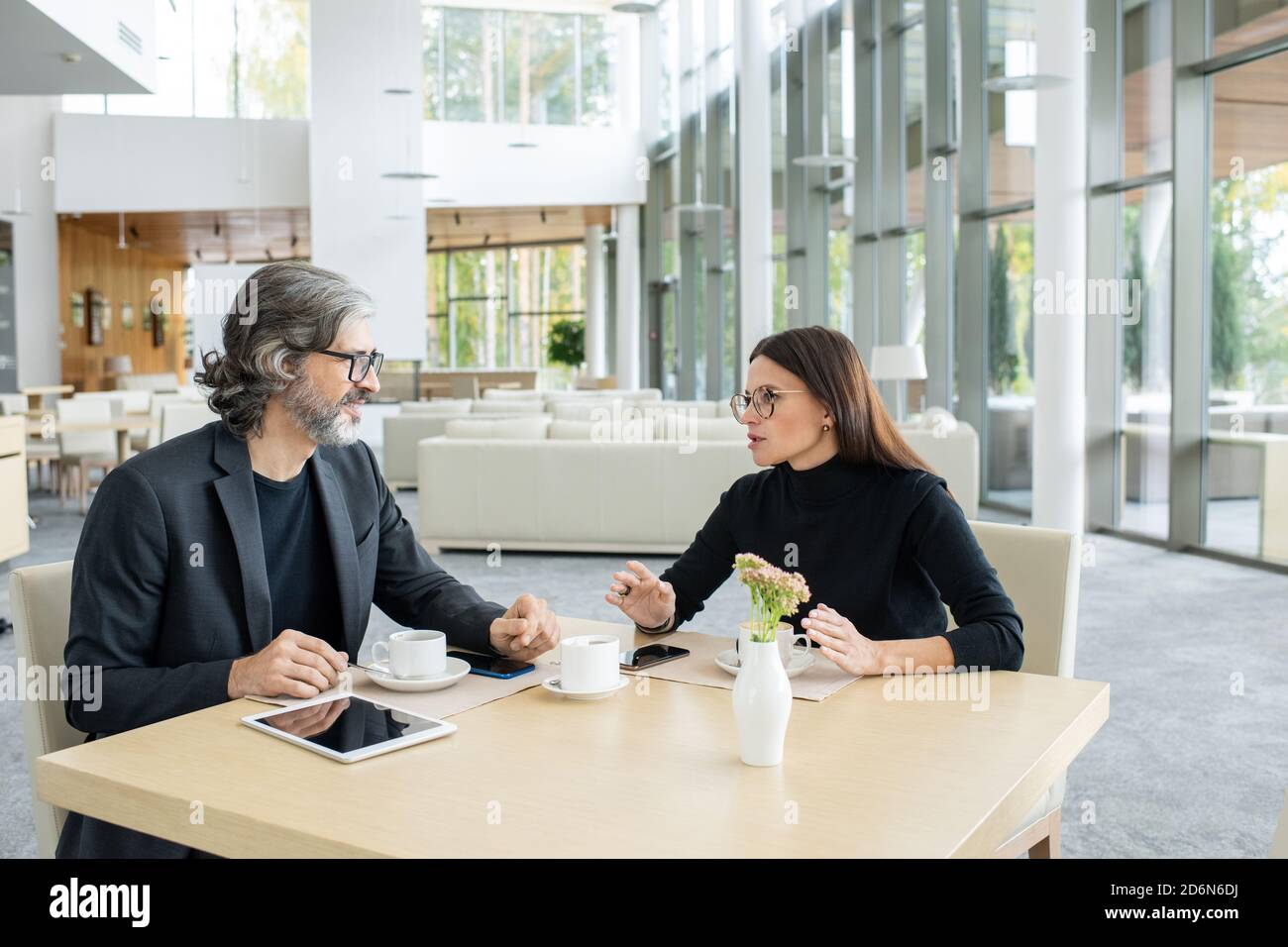 Zwei selbstbewusste Kollegen diskutieren bei einem Meeting im Restaurant über Finanznachrichten Stockfoto