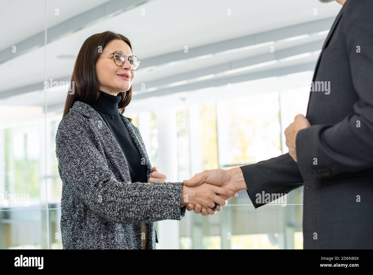 Moderne junge erfolgreiche Geschäftsfrau schüttelt die Hand des Geschäftspartners Stockfoto