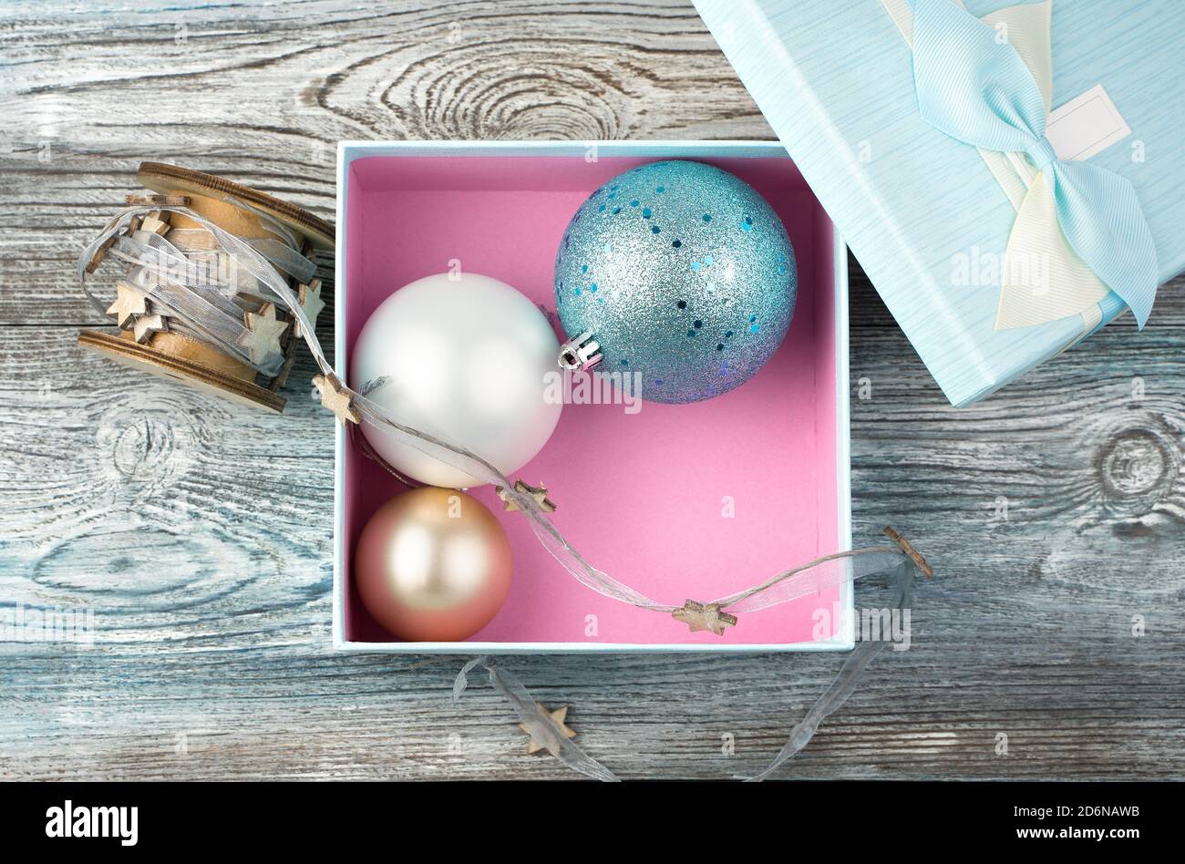 Weihnachtskugeln in einer blauen Box auf einem Holzhintergrund. Stockfoto