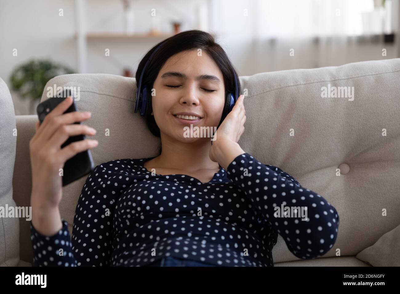 Glückliche asiatische Frau genießen Sie Musik auf dem Handy in kabellosen Kopfhörern Stockfoto