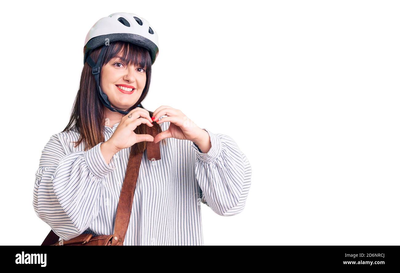 Junge plus size Frau trägt Fahrradhelm und Ledertasche lächelnd in der Liebe zeigt Herz-Symbol und Form mit Händen. Romantisches Konzept. Stockfoto