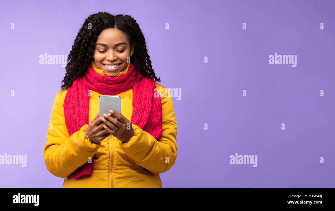 Afroamerikanische Frau Mit Smartphone Texting Über Purple Studio Hintergrund Stockfoto