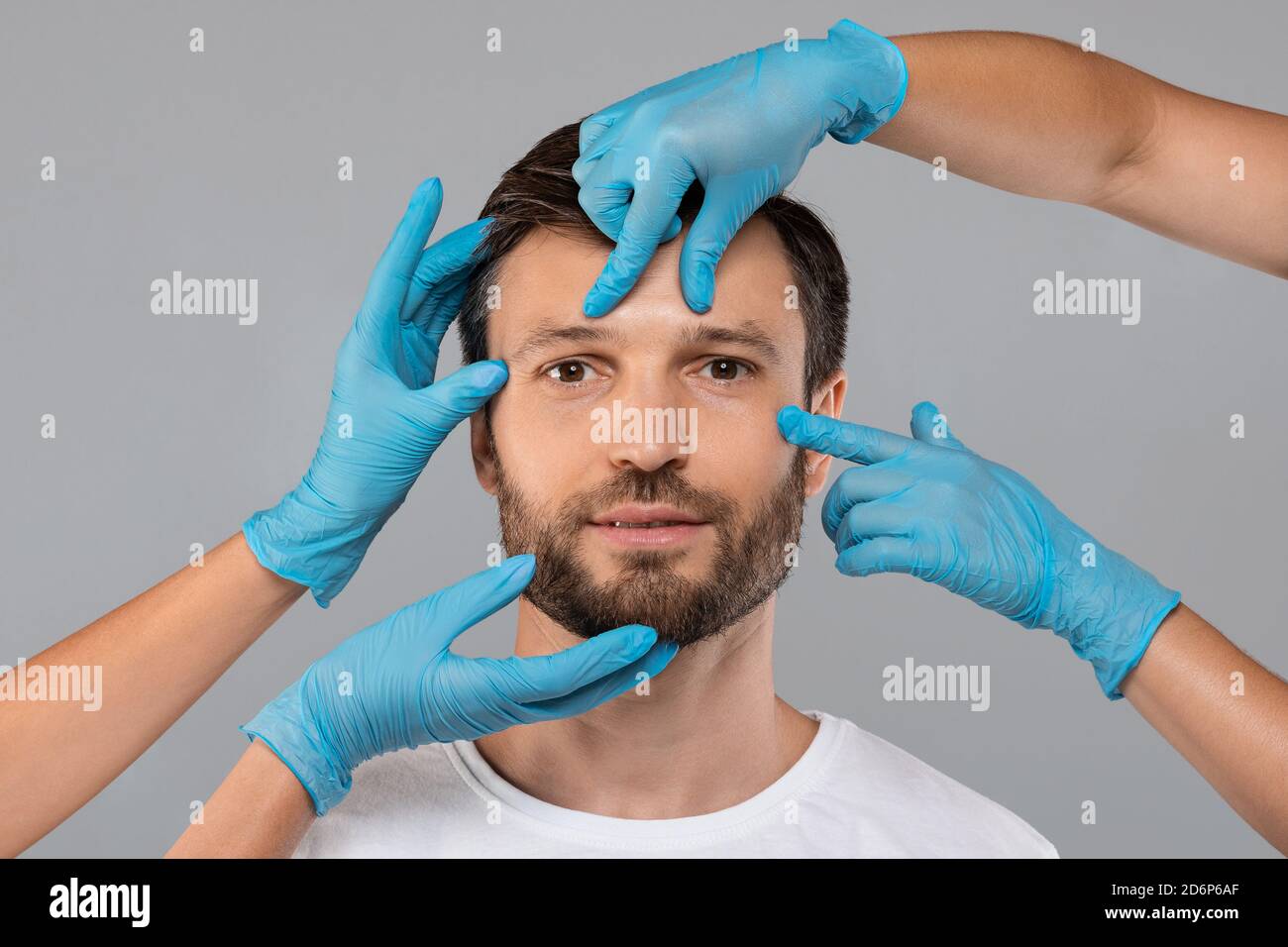 Ärzte Hände in Schutzhandschuhen berühren mittleren Alters Mann Gesicht Stockfoto