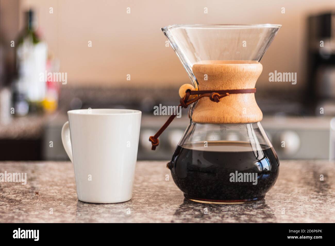Hispanische Barista gießt Kaffee in eine weiße Tasse in der Familienküche. Schwarze Frau hält gießen über Kaffeekanne am Morgen Stockfoto