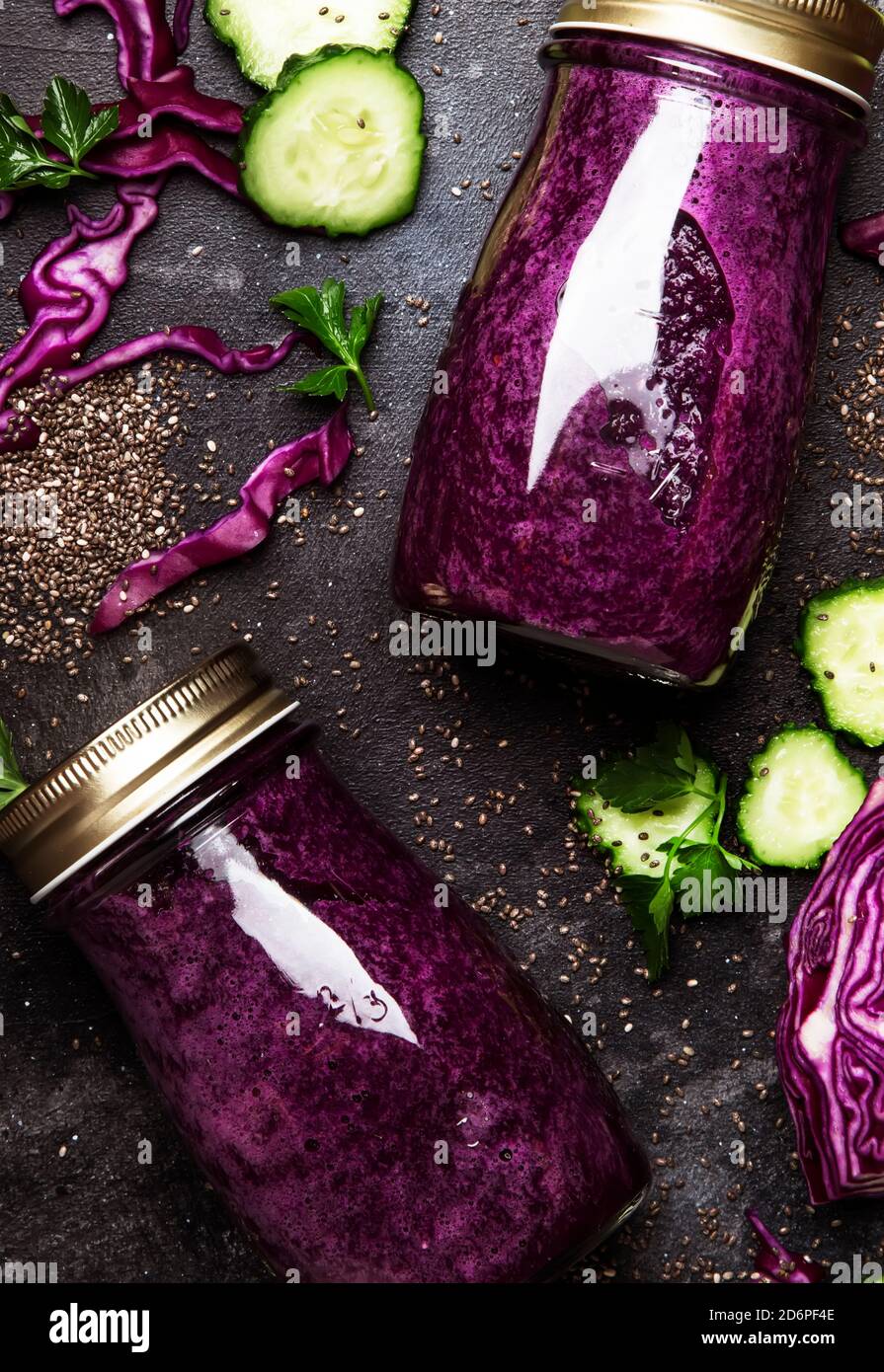 Gesunde Detox-Smoothies oder Saft aus Rotkohl, Gurken mit Chiasamen in Glasflaschen auf grauem Küchentisch-Hintergrund, veganes Fitness-Getränk CO Stockfoto