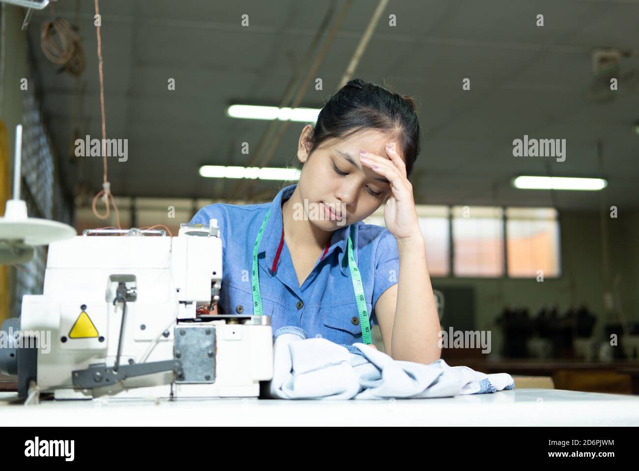 Schneiderinnen halten sich beim Nähen wegen Stress am Kopf Kleidung in der Bekleidungsindustrie Stockfoto