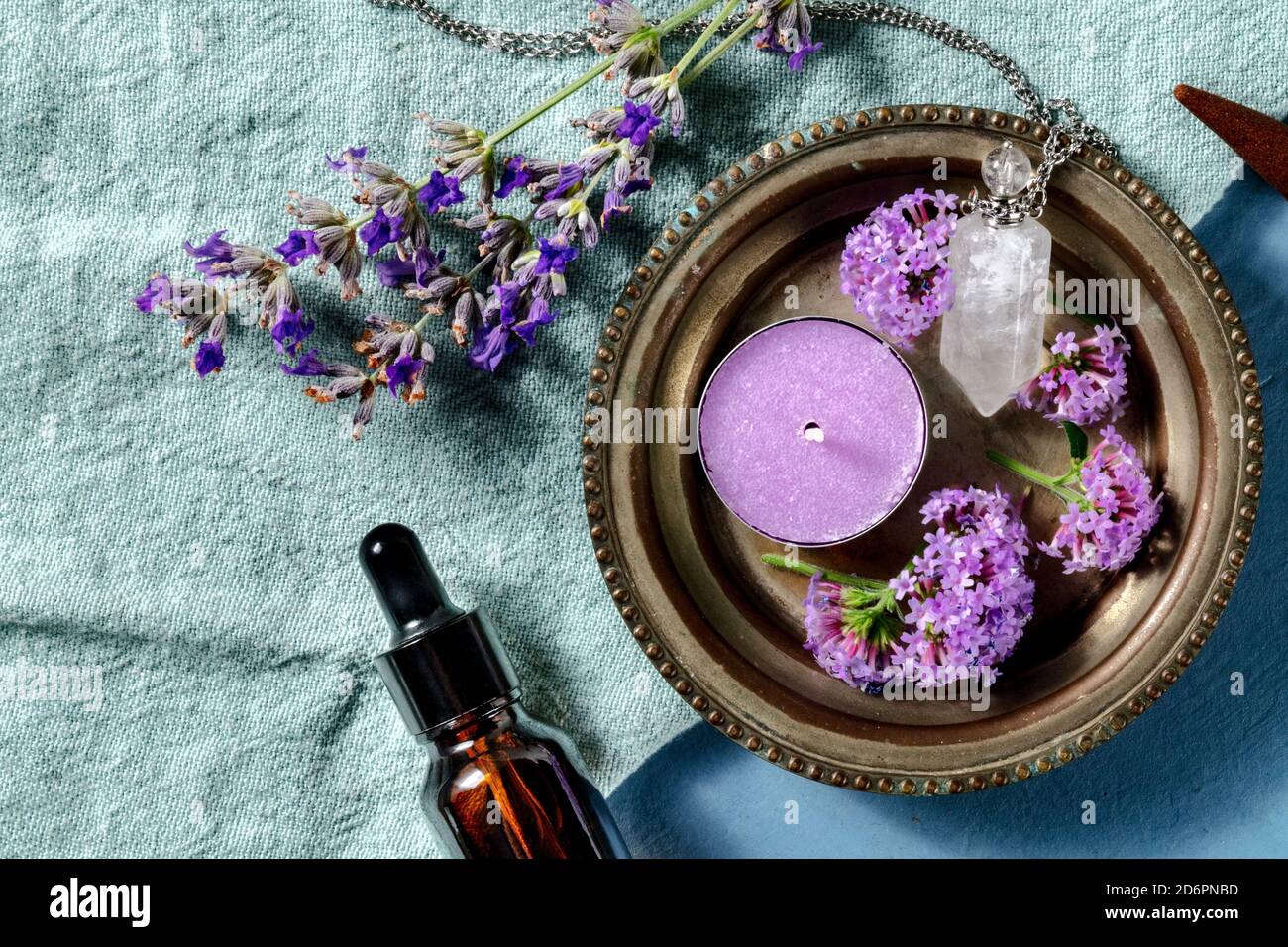Ätherisches Öl und sein Nutzungskonzept mit Kopierraum. Aromatische Kerze und ein Fläschchen für Parfüm Lavendel und Vervain, von oben auf blauem Hintergrund geschossen Stockfoto