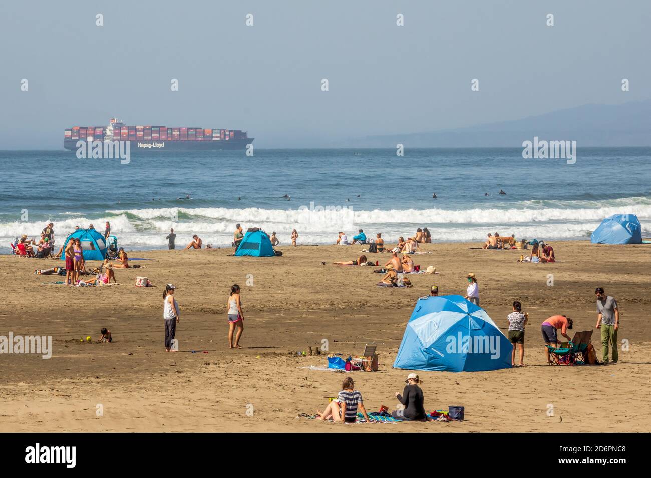 San Francisco, Kalifornien - 27. September 2020: Menschen genießen Ocean Beach mit einem Frachtschiff im Hintergrund Stockfoto