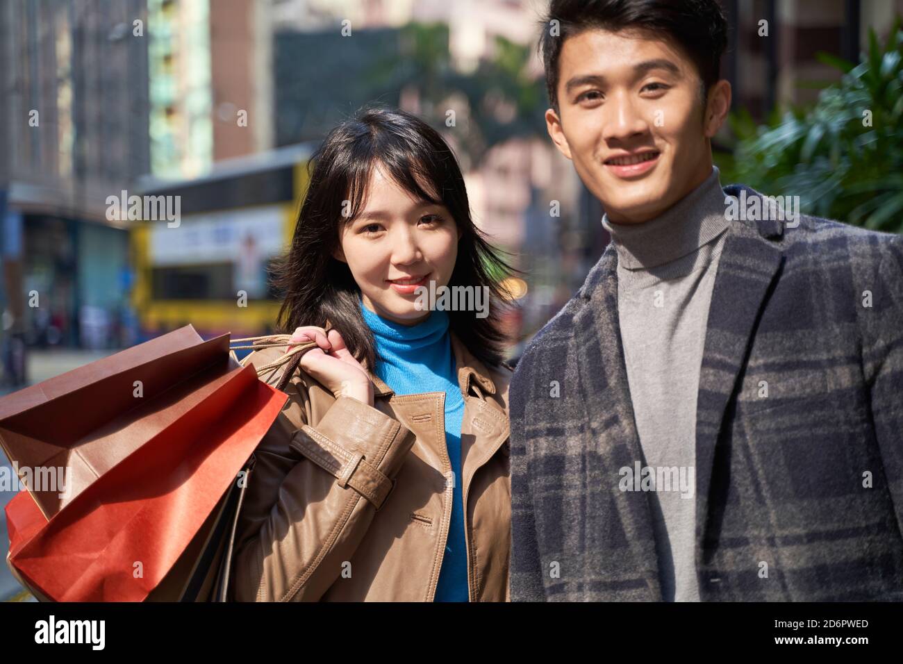 Außenportrait eines jungen liebenden asiatischen Paares mit Shopping Beutel in der Hand Stockfoto