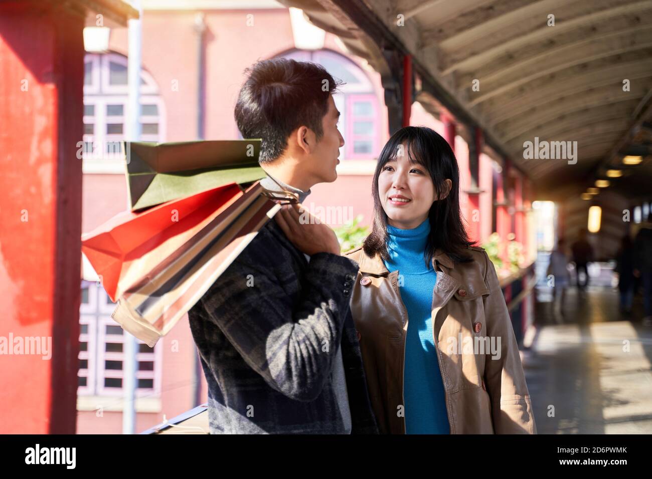 Junge liebende asiatische Paar auf einem Fußgängerüberführung halten stehen Einkaufstaschen Stockfoto