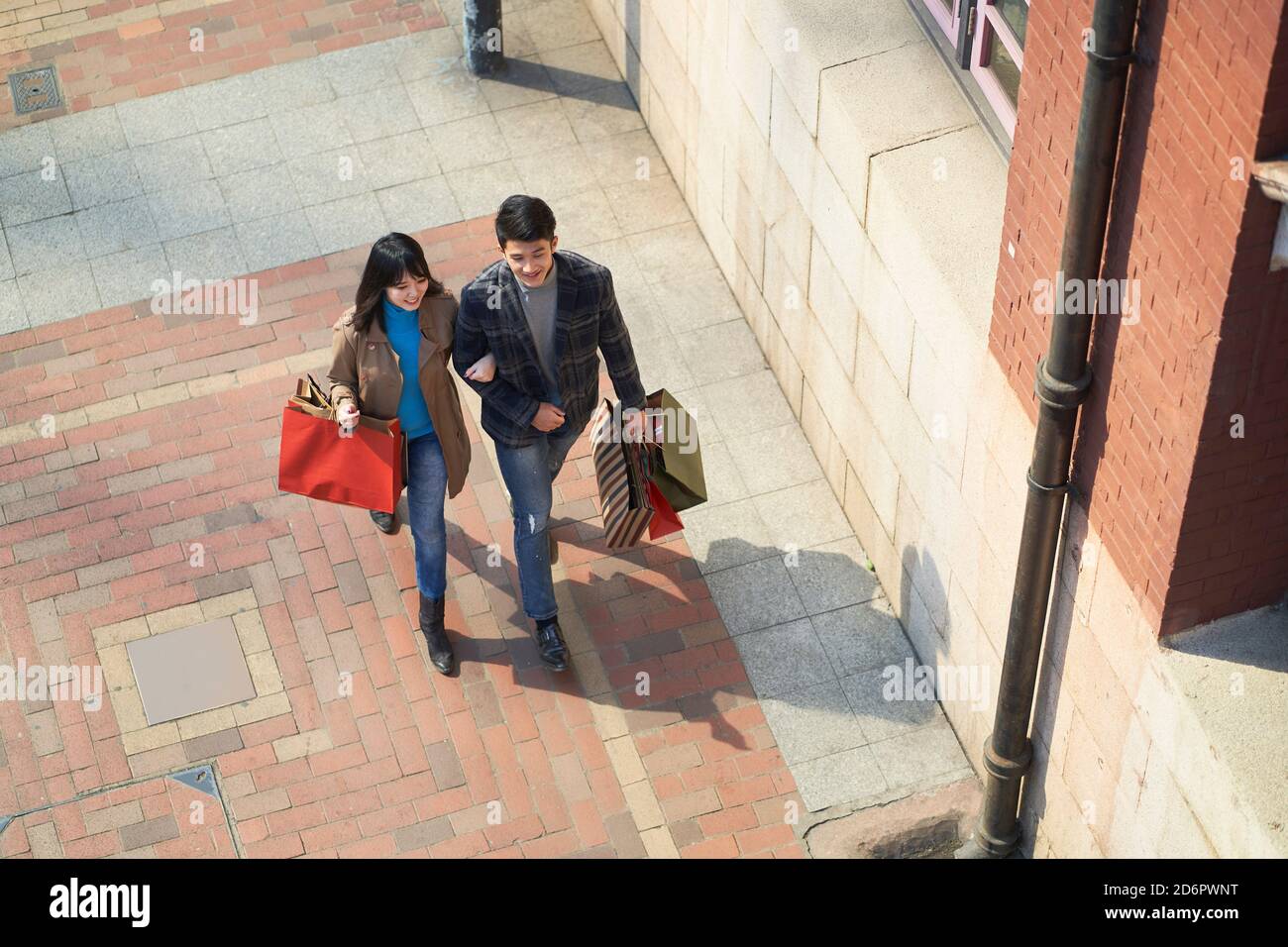 High-Winkel-Ansicht der jungen asiatischen Paar zu Fuß chatten auf Straße mit Einkaufstaschen in den Händen Stockfoto