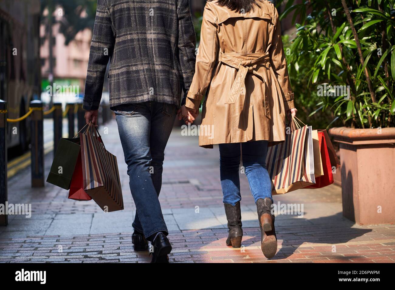 Rückansicht eines jungen asiatischen Paares, das auf der Straße läuft Einkaufstaschen in den Händen Stockfoto
