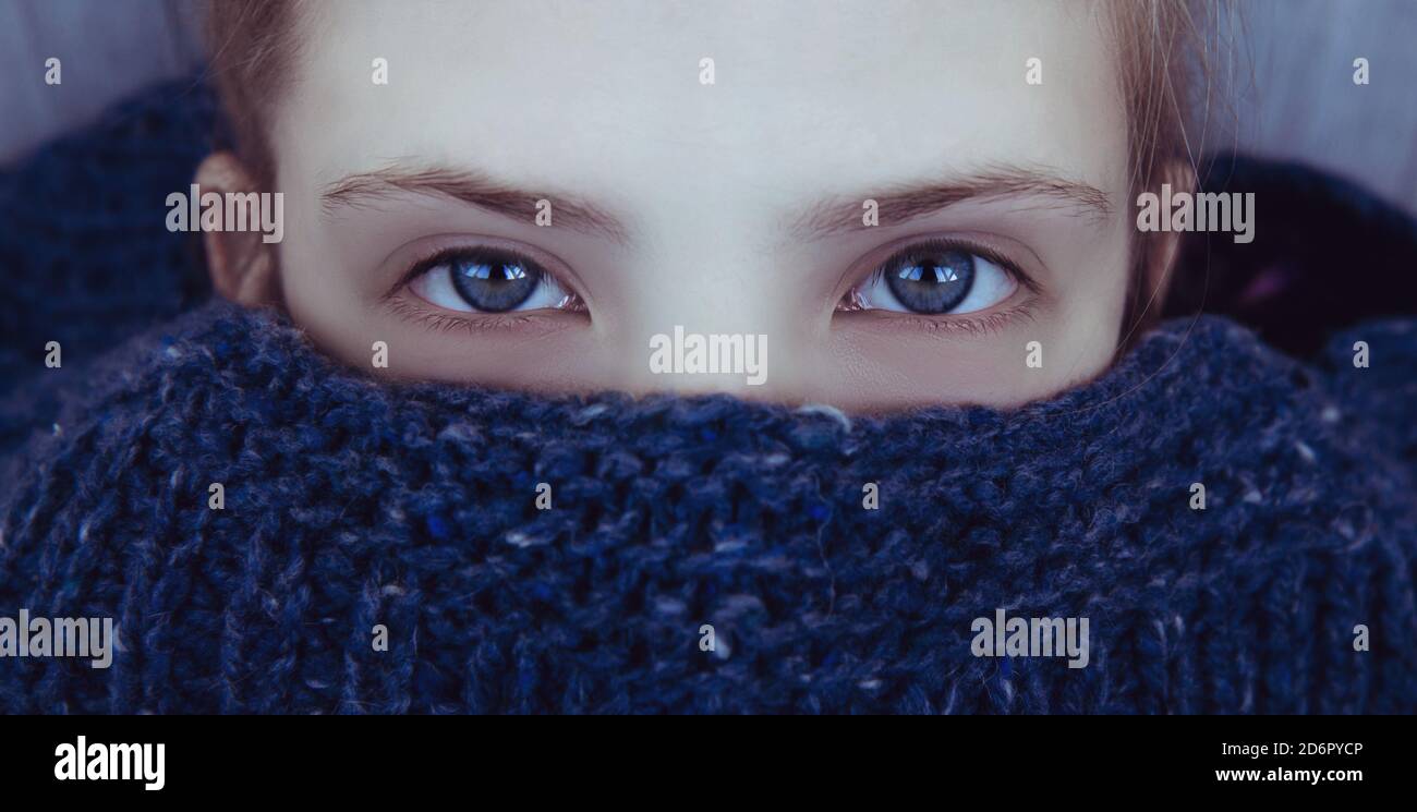 Schönes Mädchen mit blauen Augen wickelte sich in einem warmen Blauer Strickpullover Stockfoto