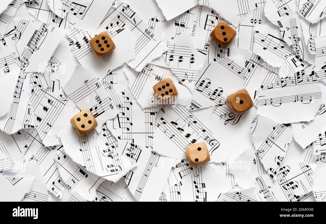 Würfel auf Papierfetzen mit Noten. Das Konzept der bedeutungslosen Musik. Stockfoto