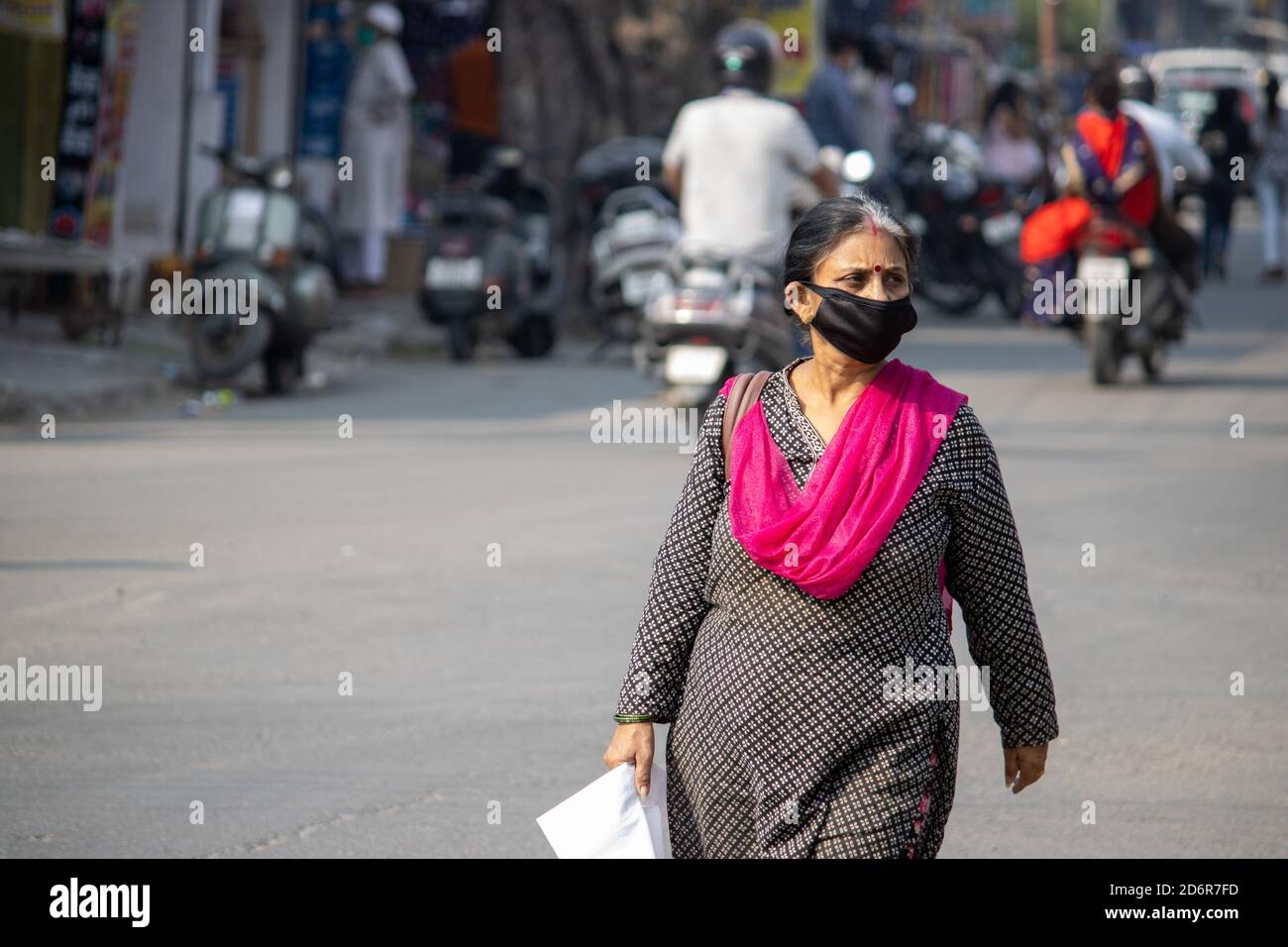 Dehradun, Uttarakhand/Indien-Oktober 14 2020:eine alte Dame mit Gesichtsmaske geht auf die indische Straße, in Corona Epidemie in Indien. . Hochwertige Fotos Stockfoto