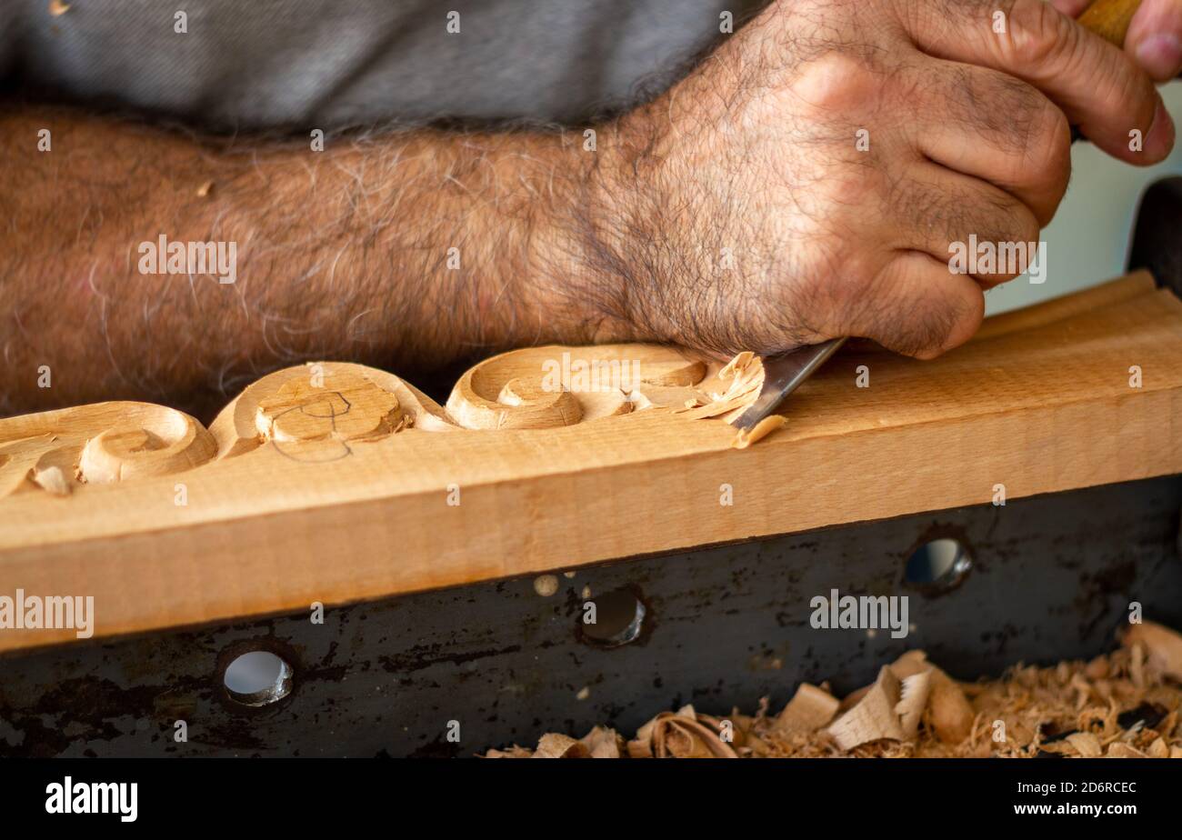 Zimmermann arbeitet an Holzmöbeln mit Handschnitzerei. Holzschnitzkunst mit Handwerkzeugen Stockfoto