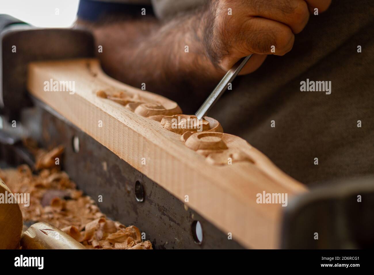 Zimmermann arbeitet an Holzmöbeln mit Handschnitzerei. Holzschnitzkunst mit Handwerkzeugen Stockfoto