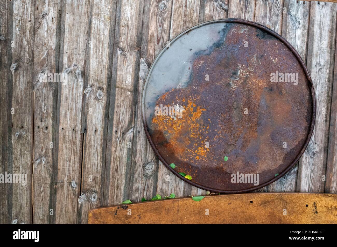 Kreis und Linien, eine Zusammenfassung eines hölzernen Zauns mit vertikalen Linien, einer verrosteten Metallscheibe als Kreis und einem dicken Holzsockel Stockfoto