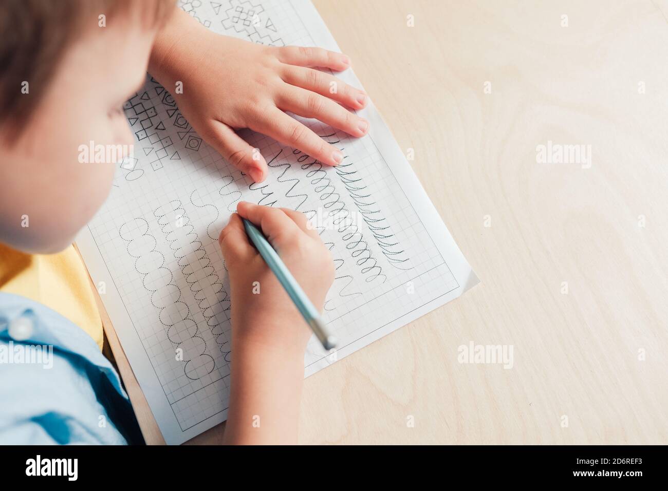 Nahaufnahme von niedlichen Jungen tun seine Hausaufgaben. Kind schreiben mit Bleistift. Vorschreiben Übung, um die Hände für das Schreiben von Briefen vorzubereiten. Konzept der Kindererziehung Stockfoto