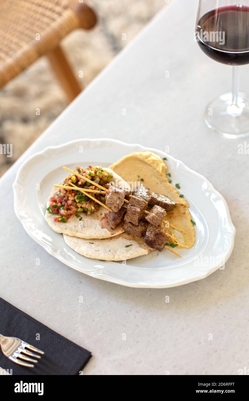 Shish Kebab mit EINEM Glas Rotwein auf einem Tisch im Restaurant Stockfoto