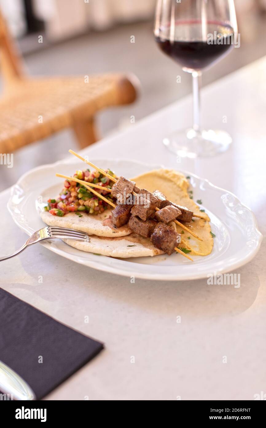 Shish Kebab mit EINEM Glas Rotwein auf einem Tisch im Restaurant Stockfoto