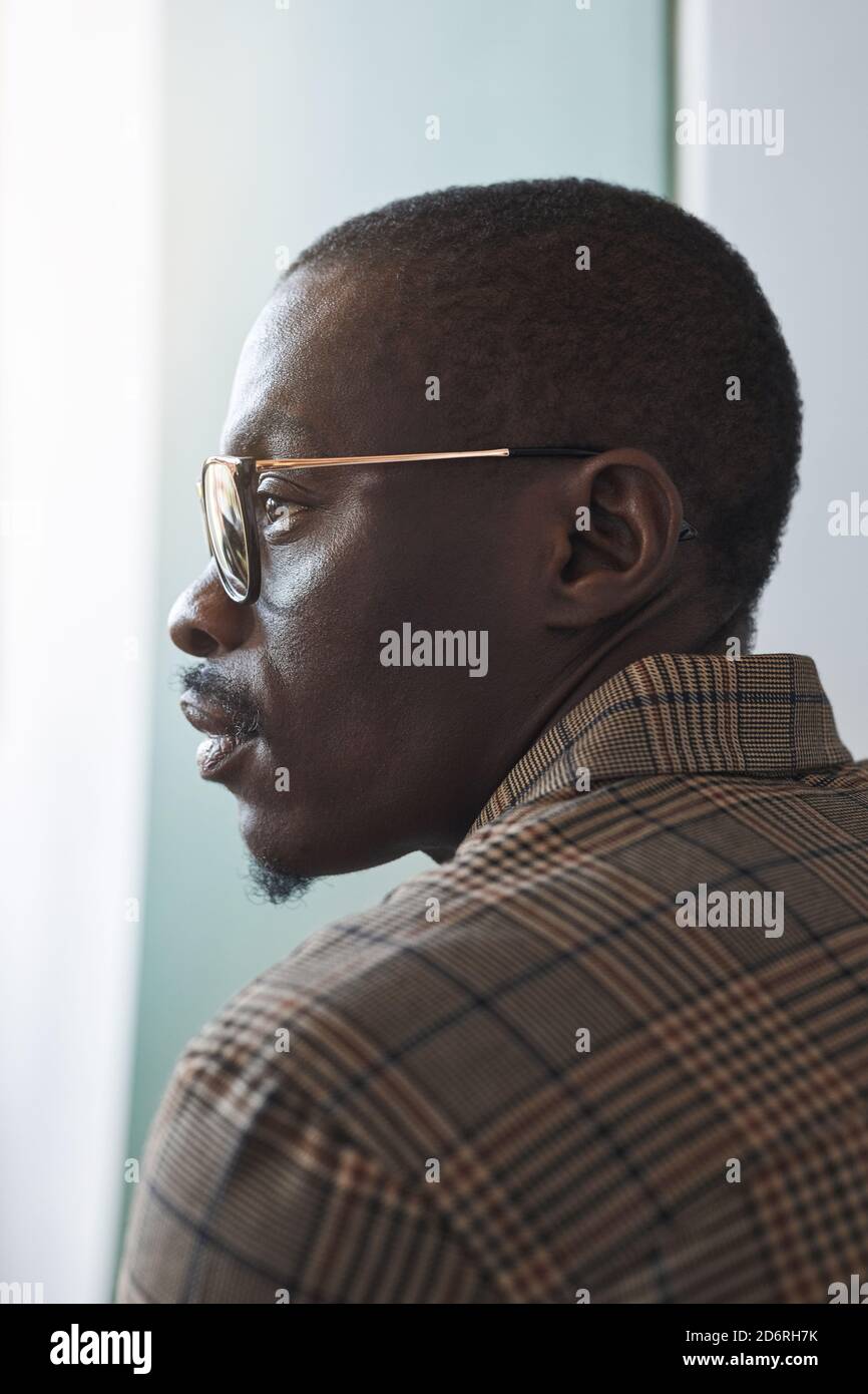 Vertikale Profilansicht Porträt von smart afroamerikanischen Gentleman trägt Brille beim Blick auf Fenster, einzigartige Beauty-Konzept Stockfoto