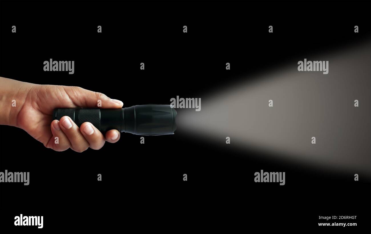Schwarze Taschenlampe in menschlichen Händen auf schwarzem Hintergrund, einschließlich eines weißen Strahls. Stockfoto