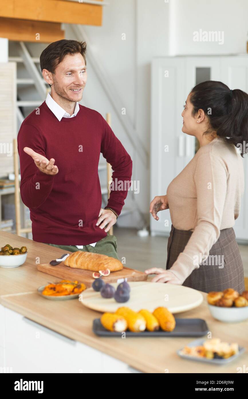 Vertikales Porträt eines erwachsenen Mannes und einer Frau, die während des Abendessens plaudern Feiern Sie drinnen mit Freunden Stockfoto