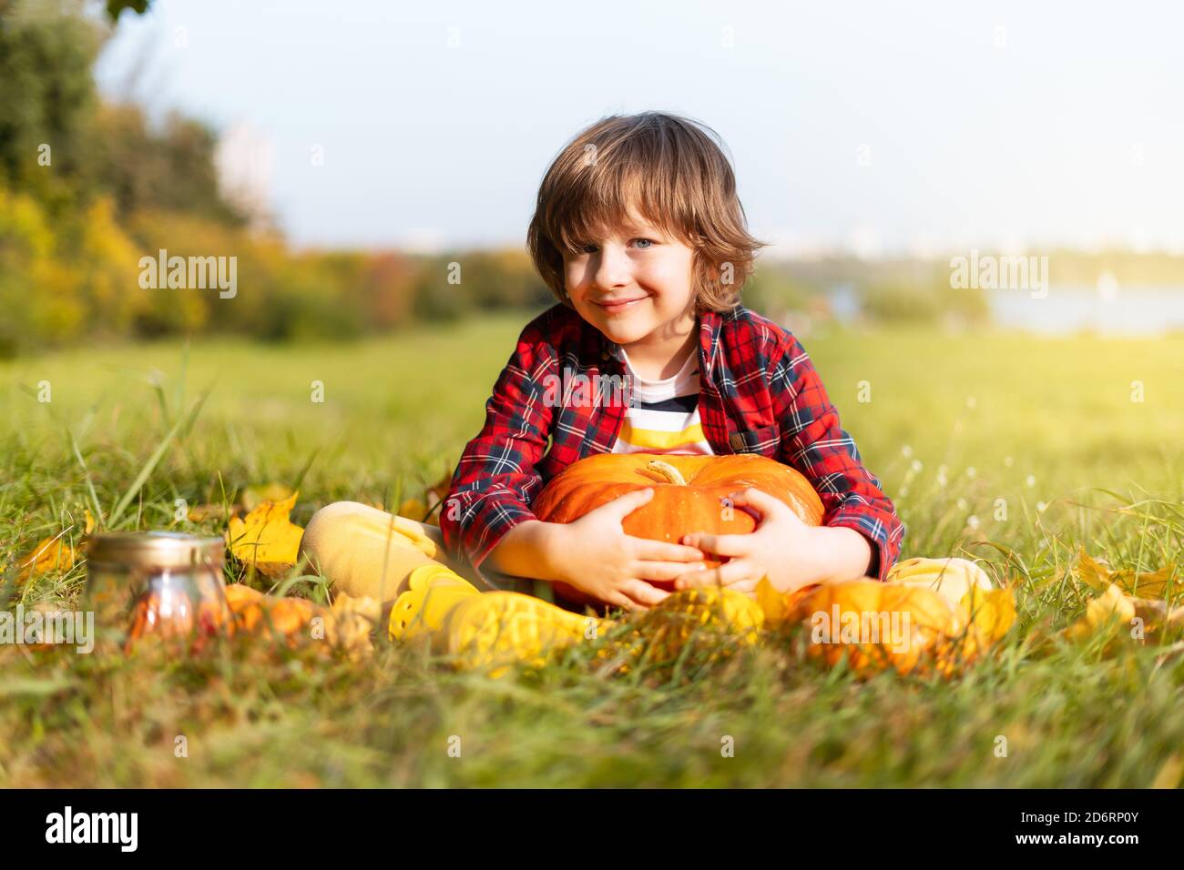 Niedlicher Junge spielen mit Kürbis im Herbstpark an Halloween. Kinder Trick or Treat. Spaß im Herbst. Verkleidetes Kind Stockfoto