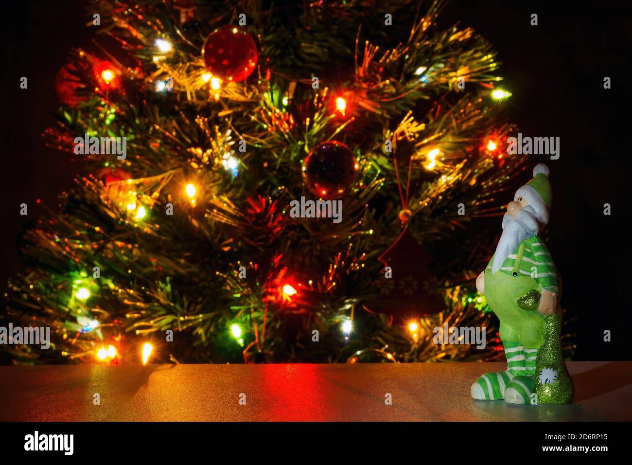 Weihnachtsmann Figur in grüner Kleidung auf Hintergrund weihnachtsbaum mit Girlande Lichter. Text kopieren, selektiver Fokus Stockfoto