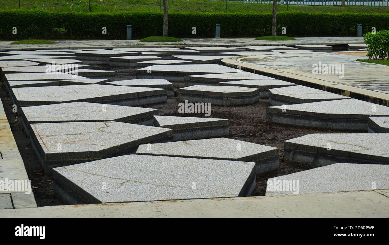 Dekorative Betonblöcke über einem künstlichen See. Dekorative unregelmäßige Betonblöcke, die über dem Wasserkörper beim Park angeordnet sind. Stockfoto