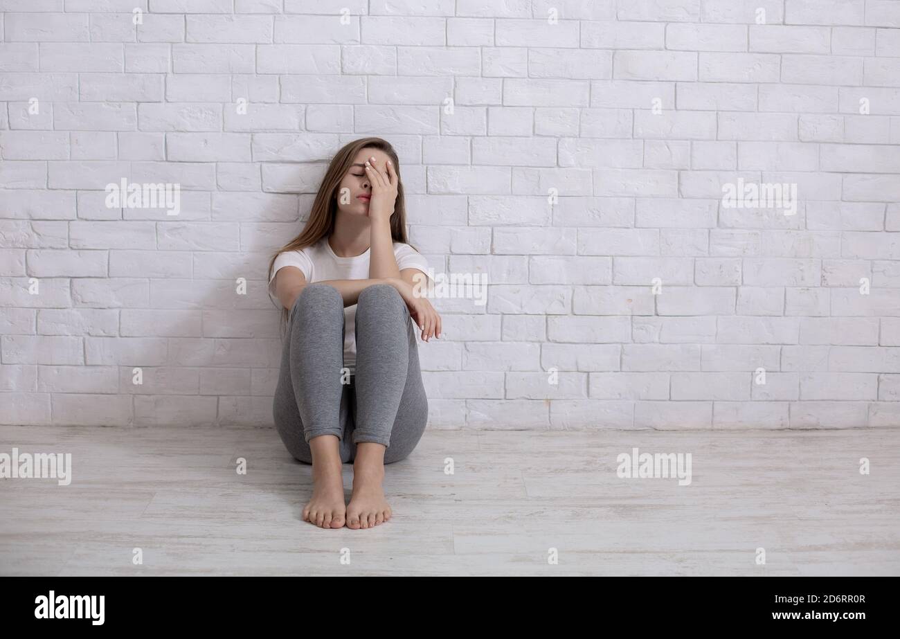 Einsame junge Frau, die zu Hause auf dem Boden sitzt, sich deprimiert und hoffnungslos fühlt, Raum kopieren Stockfoto