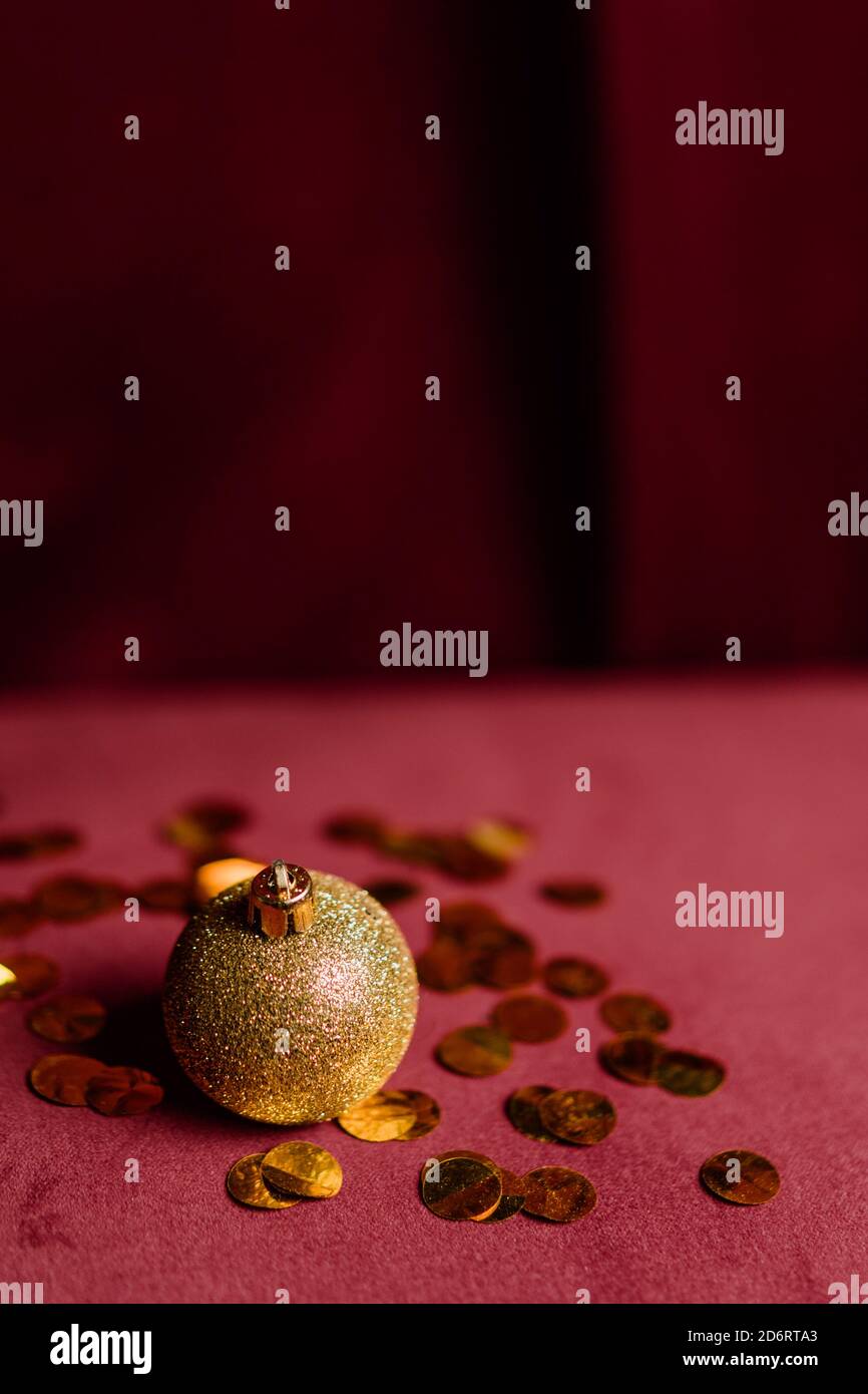 Glitzernder goldener Weihnachtsball auf weichem Bett zu Hause platziert Mit verstreuten glänzenden Konfetti für den Urlaub Stockfoto